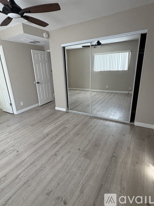 A room with a ceiling fan and sliding glass doors.