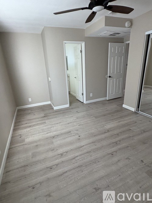 A room with a ceiling fan and light fixture, and a doorway leading to another room.