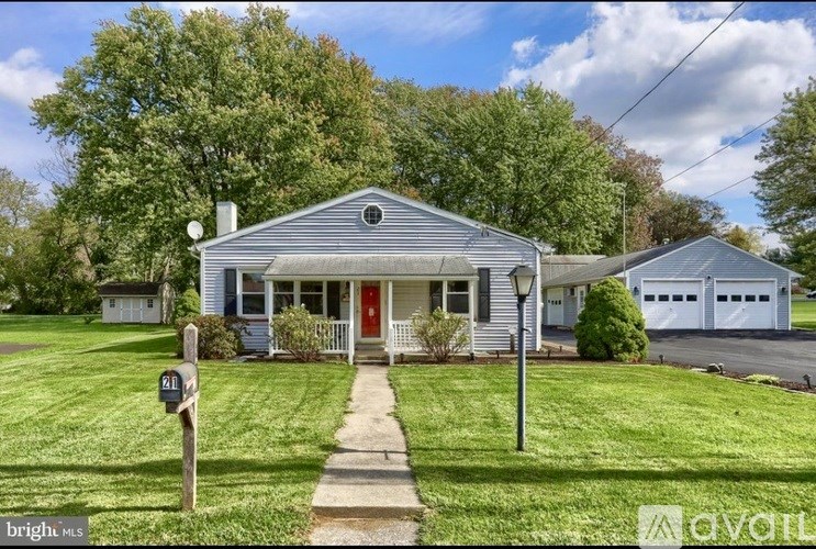 A house with a red door is surrounded by greenery.