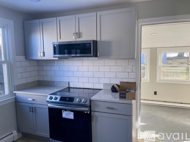 A kitchen with a black microwave above a stove and white cabinets.