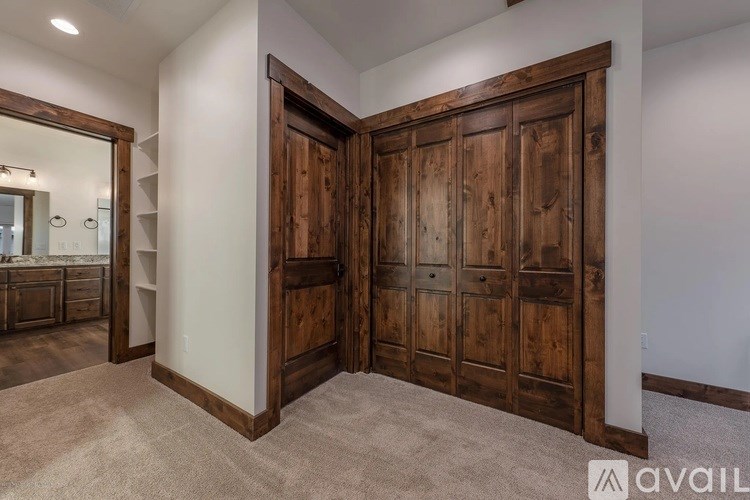 A large wooden door is open to a carpeted hallway.