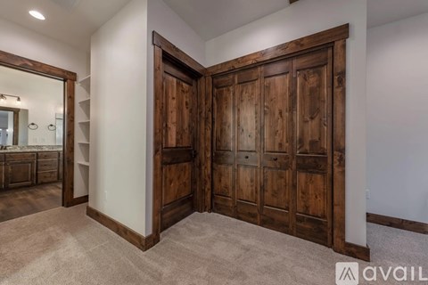 A large wooden door is open to a carpeted hallway.