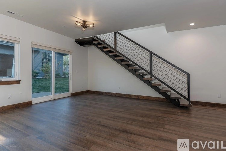 A room with a wooden floor and a staircase with a metal railing.