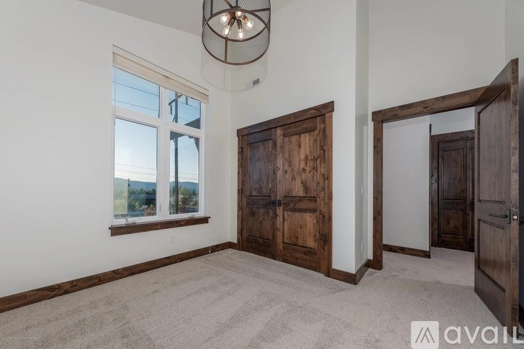 A room with a large window, a wooden door, and a carpeted floor.