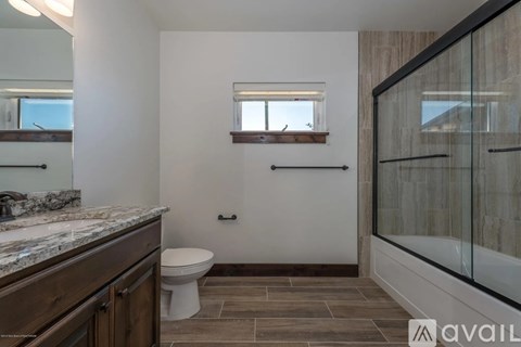 A bathroom with a toilet, sink, and a window.