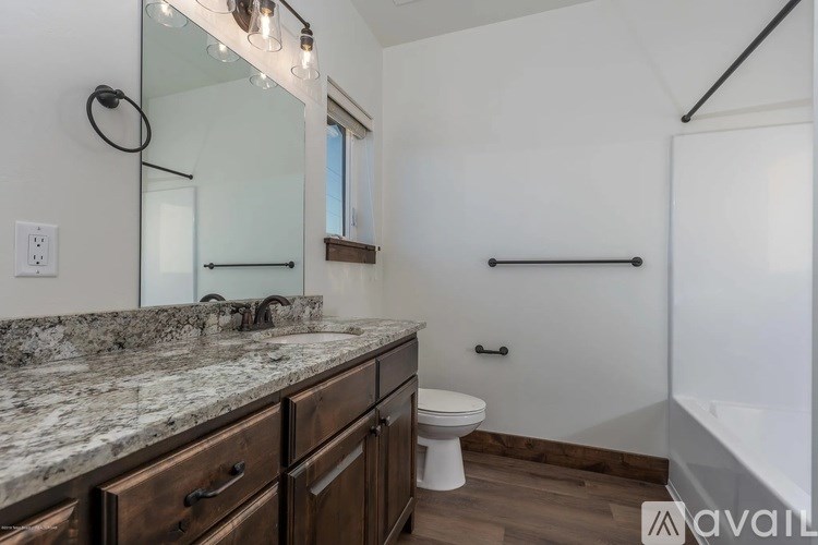 A bathroom with a marble countertop and wooden cabinets.