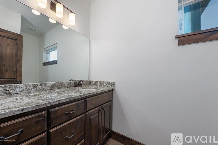 A bathroom with a marble countertop and wooden cabinets.