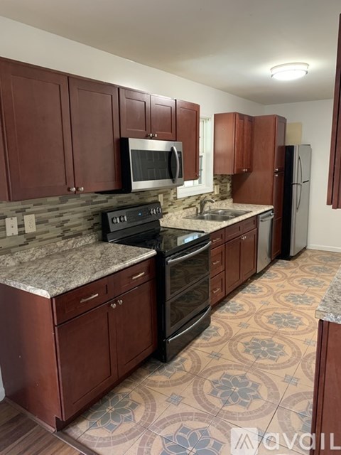 A kitchen with brown cabinets and a patterned floor.