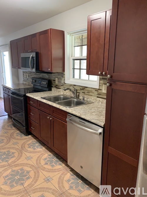 A kitchen with brown cabinets and a white dishwasher.
