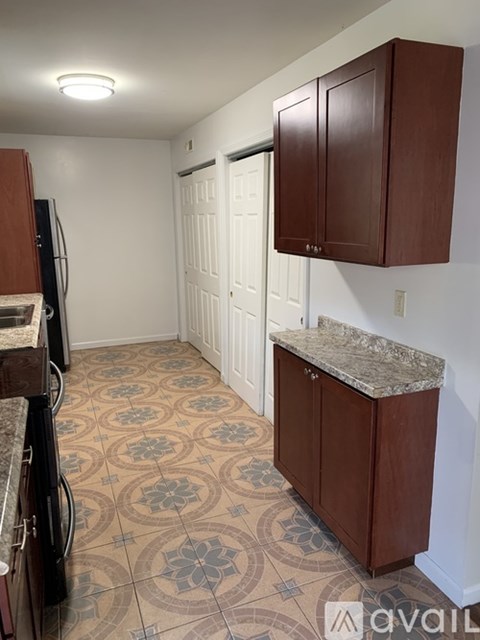 A kitchen with brown cabinets and a patterned floor.