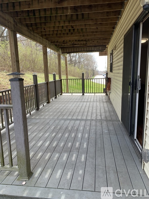 A wooden deck with a railing and a view of a grassy area.