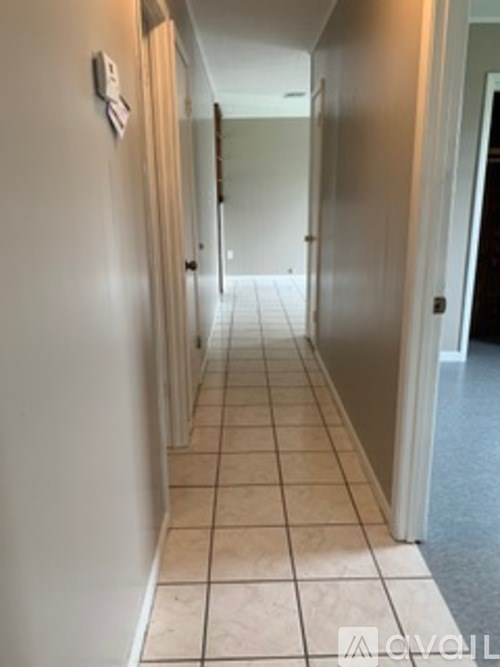 A long hallway with tiled floors and white walls.