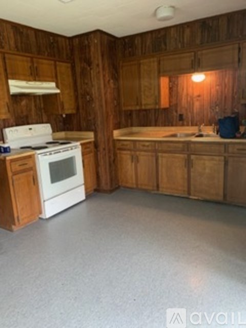 A kitchen with wooden cabinets and a white stove.