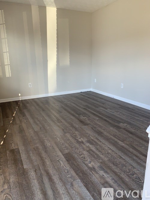 A room with wooden flooring and white walls.