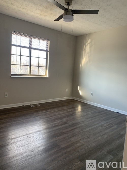 A room with a ceiling fan and a window with blinds.