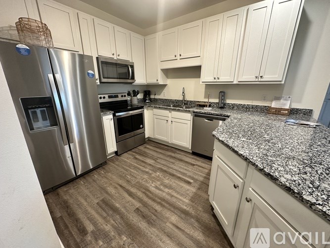 A kitchen with white cabinets and a granite countertop.