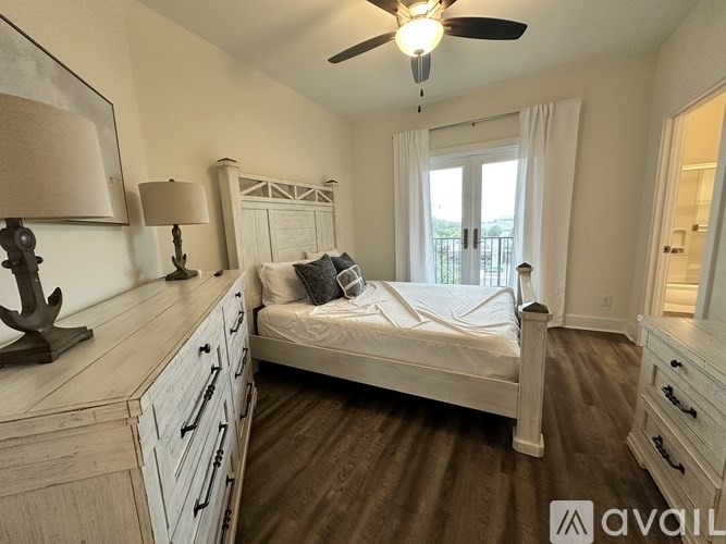 A bedroom with a bed, dresser, and ceiling fan.