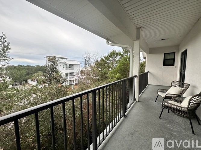A balcony with a chair and a table overlooking a residential area.