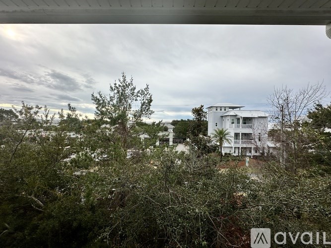 A white house is surrounded by greenery and trees.