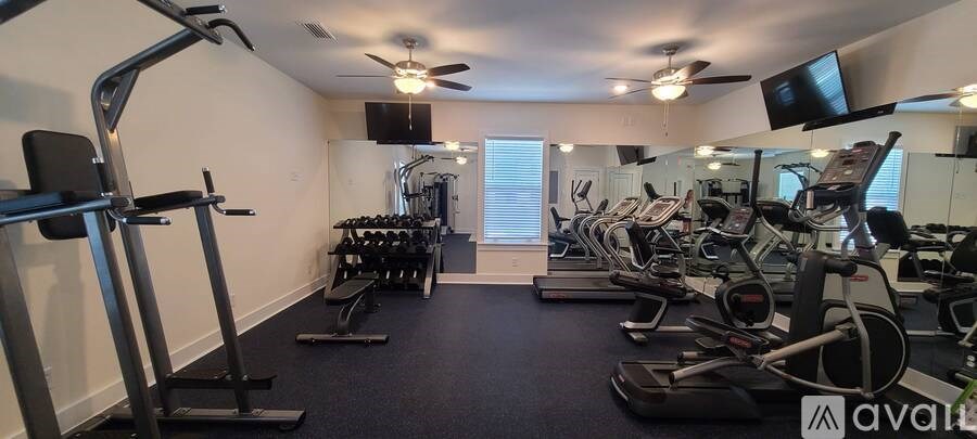 A gym with a variety of equipment including treadmills, weights, and a television.