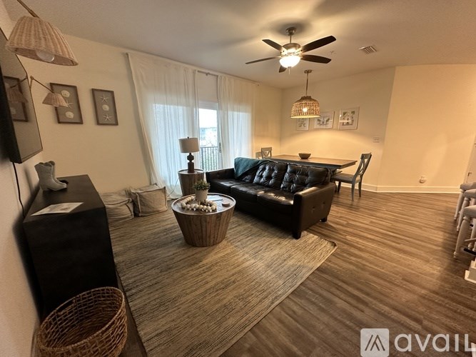 A living room with a black couch, a wooden floor, and a ceiling fan.