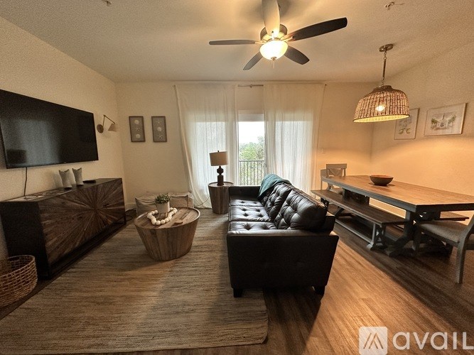 A living room with a black couch and a wooden floor.