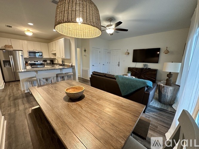 A modern kitchen with a wooden dining table and a ceiling fan.