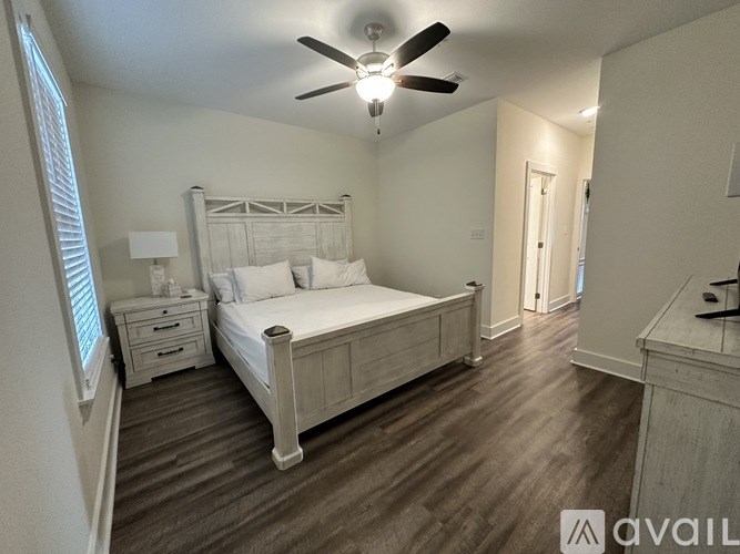 A bedroom with a bed, dresser, and ceiling fan.