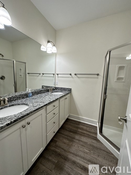 A bathroom with a granite countertop and a walk-in shower.