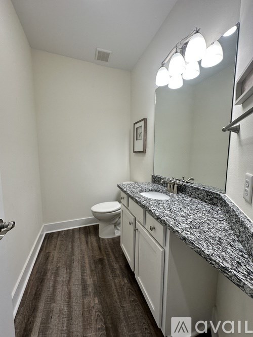 A bathroom with a toilet, sink, and mirror.