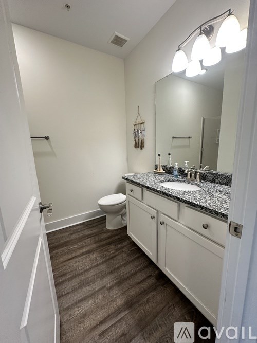A bathroom with a toilet, sink, and mirror.