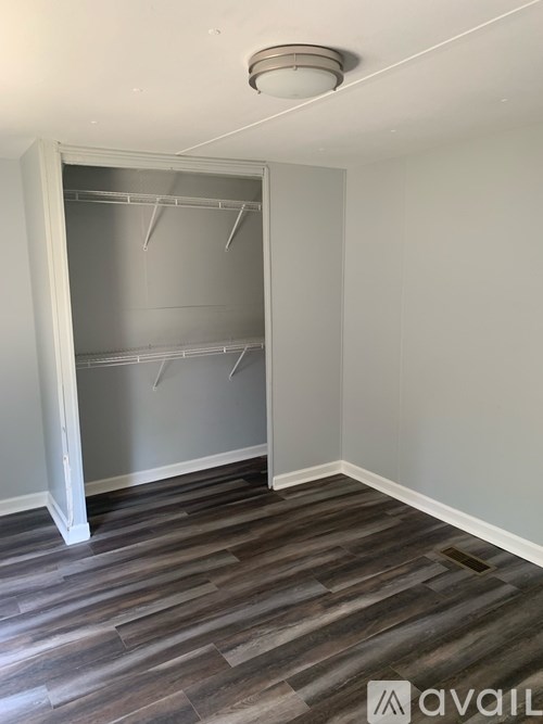 Empty room with a walk-in closet and wooden flooring.