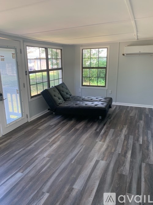 A room with a black couch and wooden flooring.