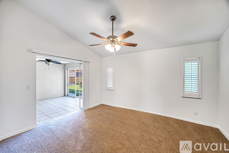 A room with a ceiling fan and a window with blinds.