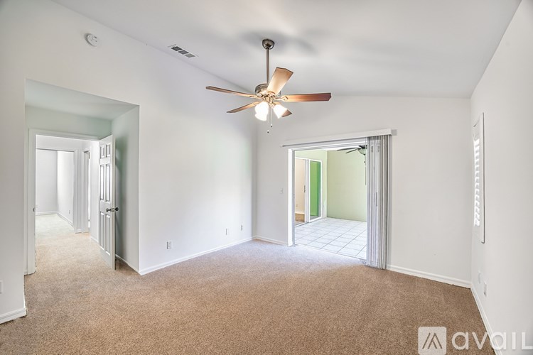 A room with a ceiling fan and carpeted floor.