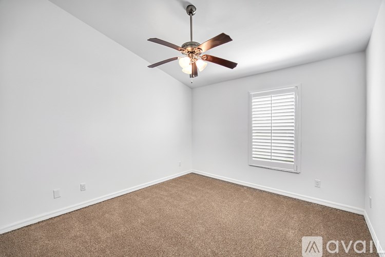 A room with a ceiling fan and carpeted floor.