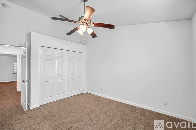 A room with a ceiling fan and a white door.