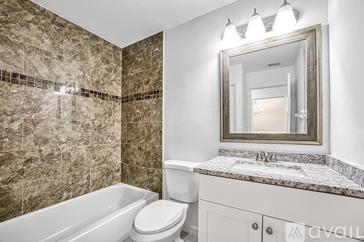 A bathroom with a marble tile wall and a white bathtub.