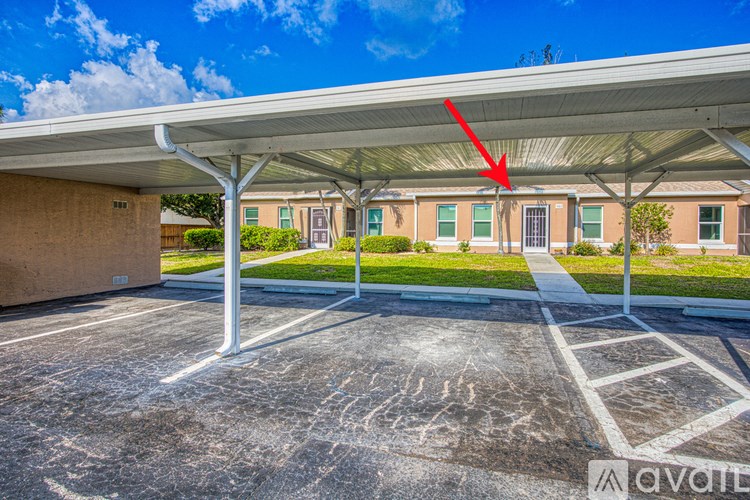 A parking lot with a building in the background and a red arrow pointing to the roof of the building.