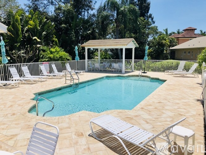 A pool with a gazebo and chairs around it.