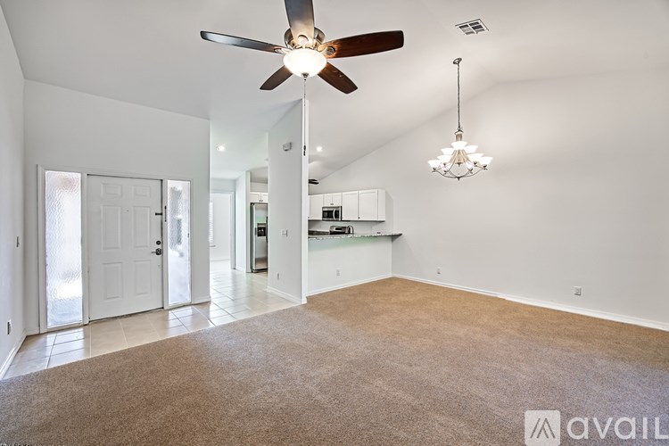 A spacious room with a ceiling fan and a chandelier.