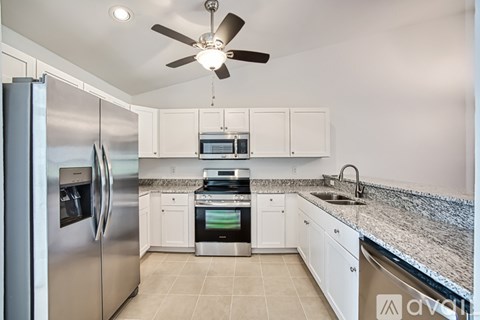 A modern kitchen with a stainless steel refrigerator and white cabinets.