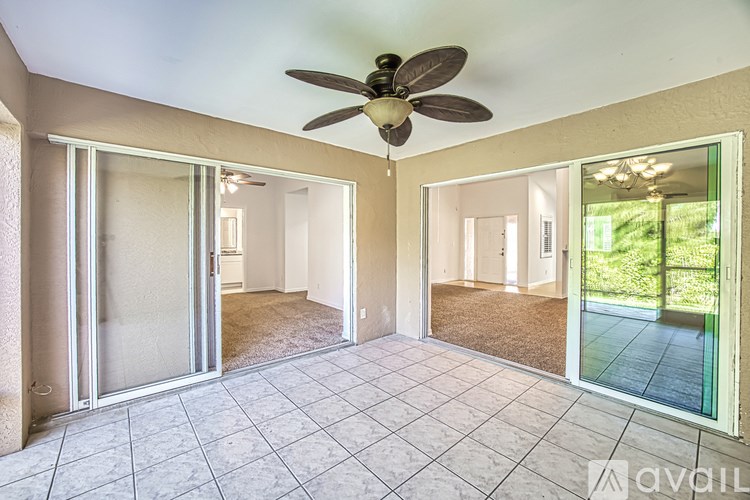 A spacious room with a ceiling fan and sliding glass doors.