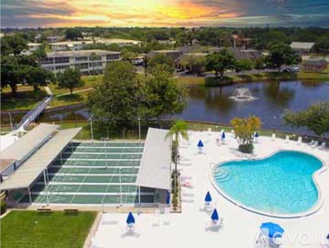 An outdoor swimming pool with a tennis court and a fountain in the background.