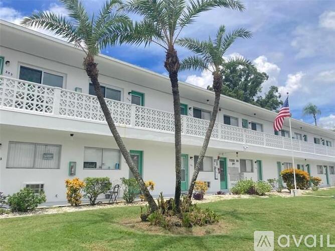 A white building with green trim and a balcony with an American flag hanging from it.