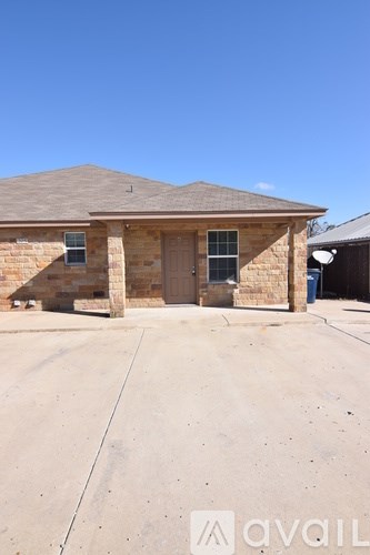 A house with a brown roof and a brown brick wall with a garage door.