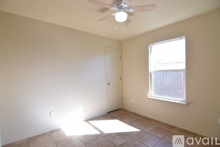 A room with a ceiling fan and a window letting in sunlight.