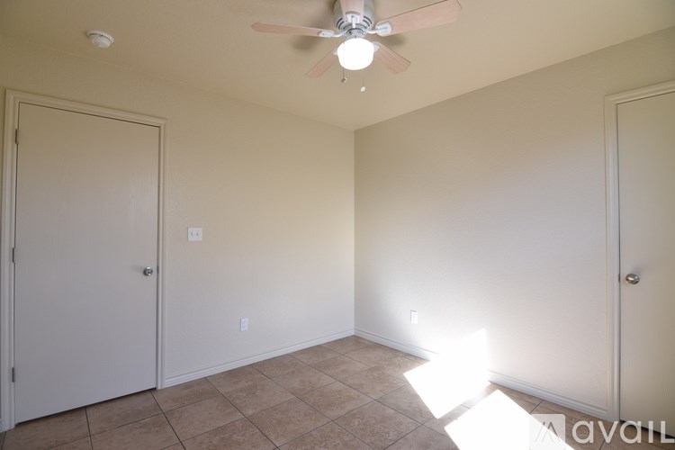 A room with a ceiling fan and two doors.