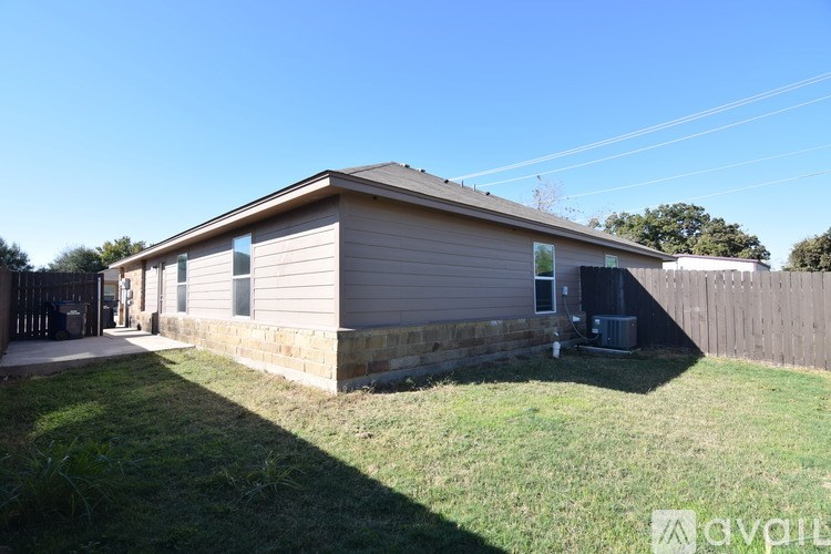 A small house with a fence and a lawn in front.