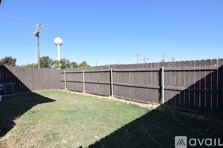 A backyard with a wooden fence and a water tower in the background.